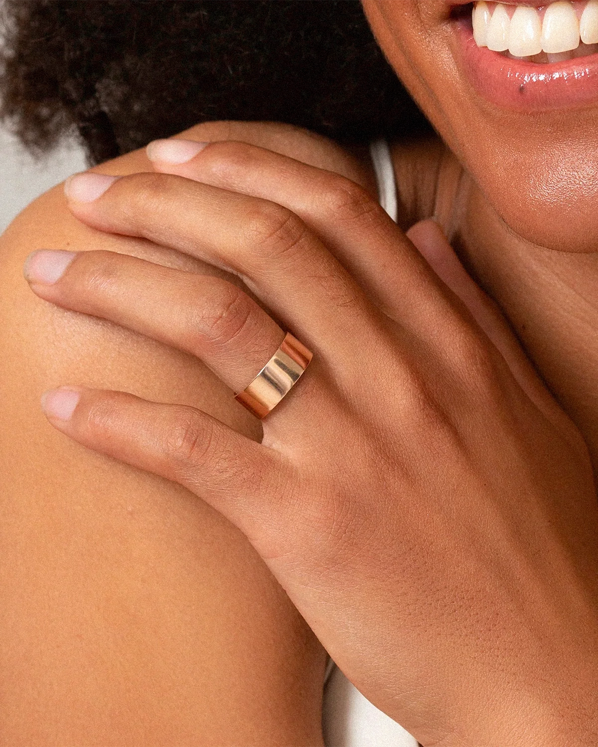 Close-up of a hand wearing a gold ring with a blurred background