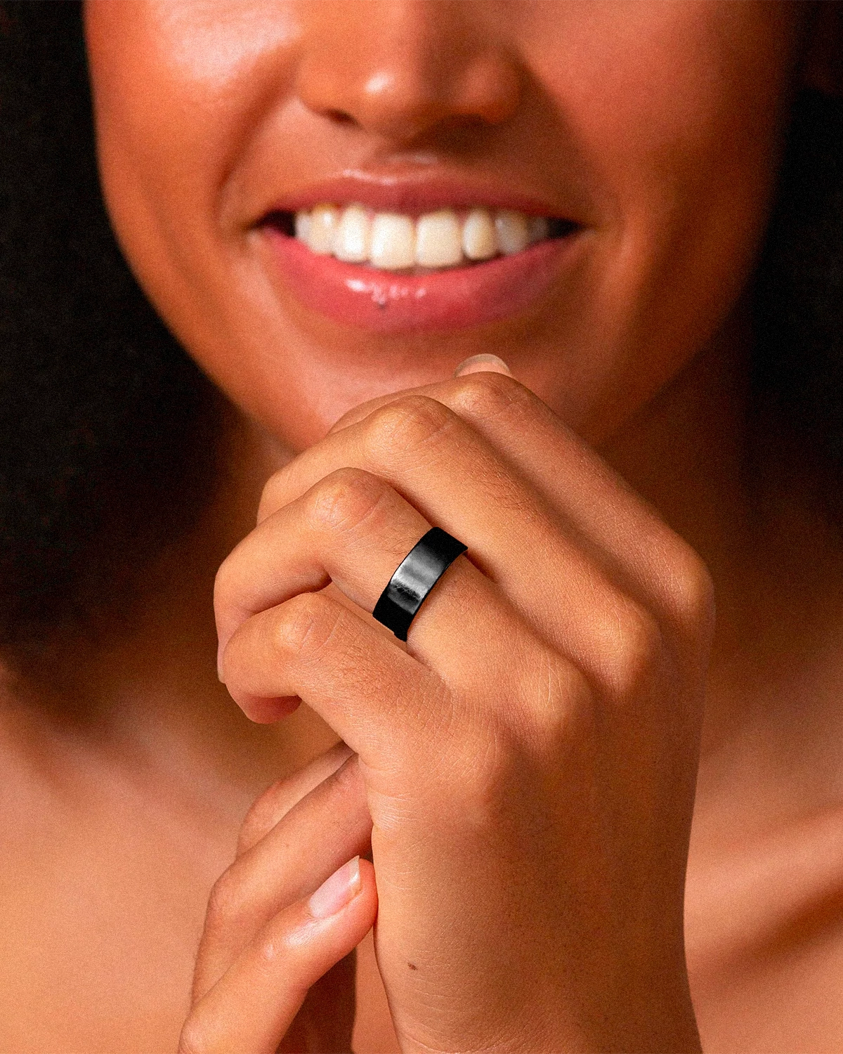 Close-up of a person wearing a black ring on a blurred background