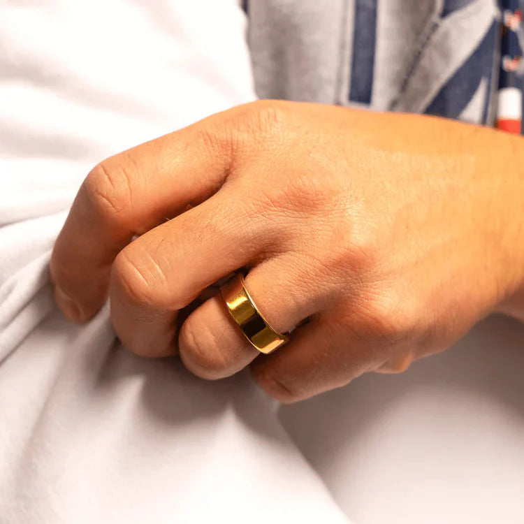 Hand wearing a gold ring on a white background